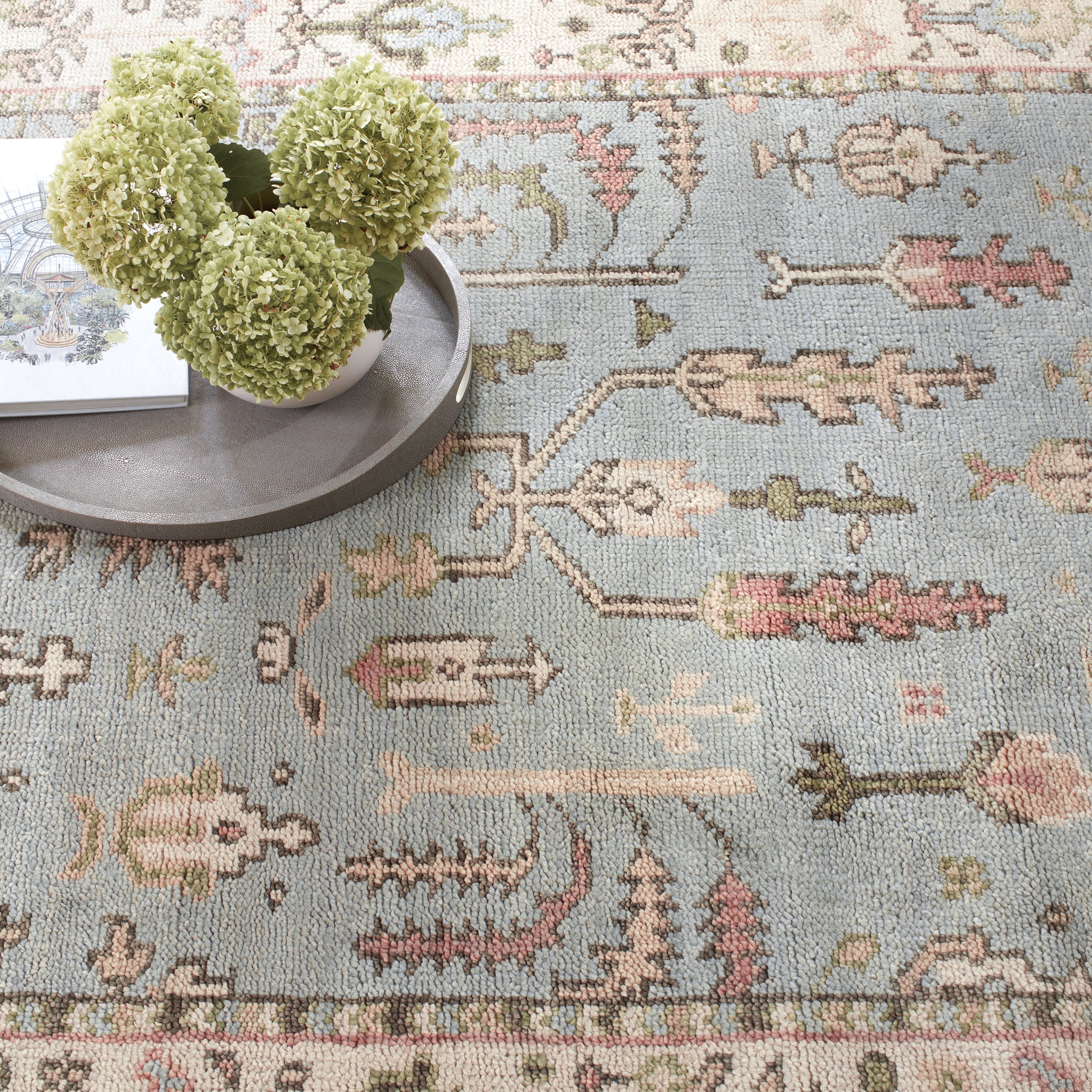 Beige armchair on a patterned rug in a room with wooden table and decorative elements.